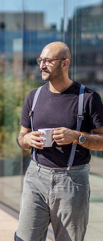A person waling while holding a coffee mug. 